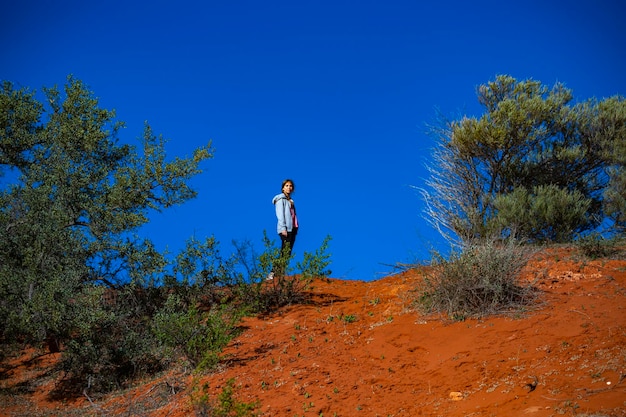 langharig meisje dat in australische rode zandwoestijn terra rosa in francois peron nationaal park wandelt