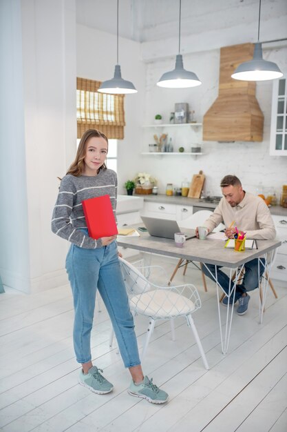 Langharig meisje in grijs overhemd met een rood boek