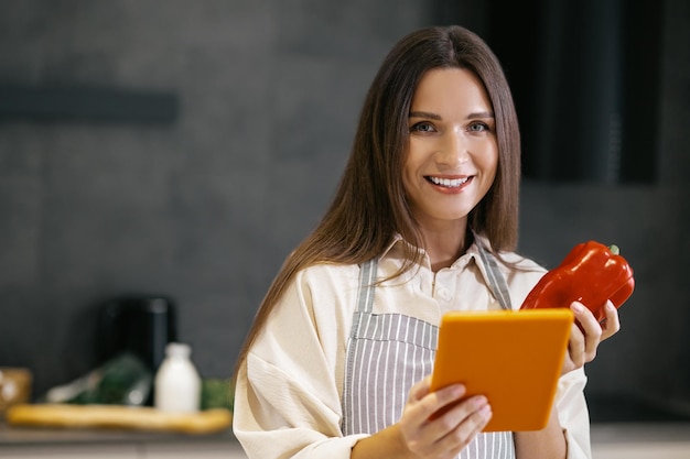 Langharige jonge vrouw die erover denkt iets te koken voor de lunch