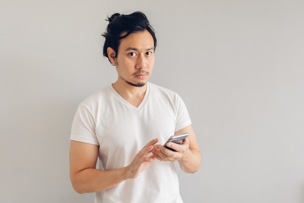 Langharige man in witte casual t-shirt gebruikt smartphone