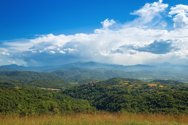 Langhe is a hilly area  in the province of Cuneo in Piedmont, northern Italy. View of the valley after a storm. Huge white clouds on a blue sky.