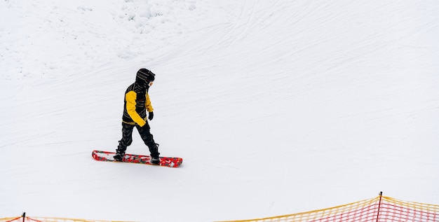 Langlaufen in prachtig winterlandschap. Mannelijke snowboarder loopt op de heuvel. Toeren in de bergen. Bewolkt weer. Sportconcept