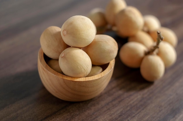 Langsat Longkong placed in a wooden cup set on a wooden board table dark blurred background