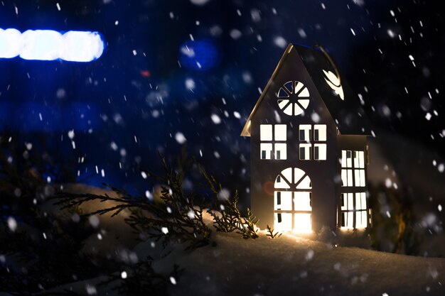 Lantaarnhuis met brandende kaars op sneeuw in de avond.