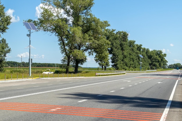 Lantaarnpaal met zonnepaneelsysteem op weg met blauwe lucht en bomen Autonome straatverlichting met zonnepanelen Straatlantaarn op batterijen van de zon Alternatieve hernieuwbare energiesystemen