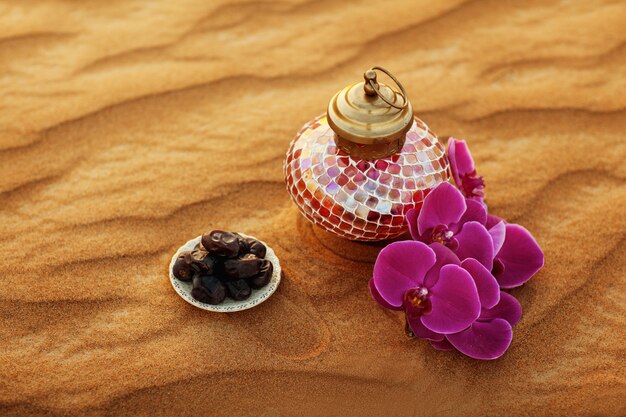 Lantern, flower and dates in the desert at a beautiful sunset, symbolizing Ramadan