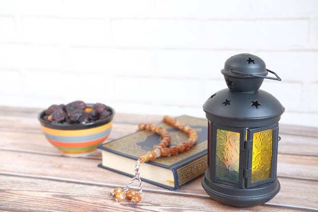 Lantern light holy book quran and rosary on table close up