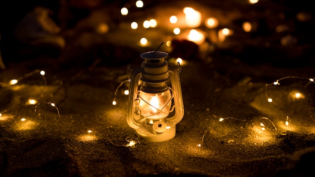 Lantern with burning garland on sand