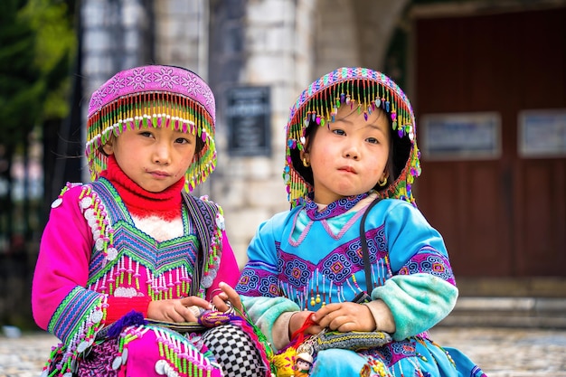 Lao Cai VIETNAM 12 maart 2023 prachtig portret van een Vietnamees meisje HMong etnische minderheid begroet toeristen die voor de kerk zitten en handgemaakte artikelen verkopen Sapa downtown