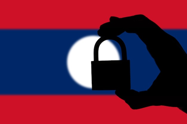 Laos-beveiliging Silhouet van de hand met een hangslot boven de nationale vlag