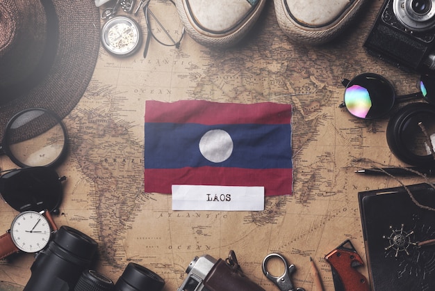 Laos Flag Between Traveler's Accessories on Old Vintage Map. Overhead Shot