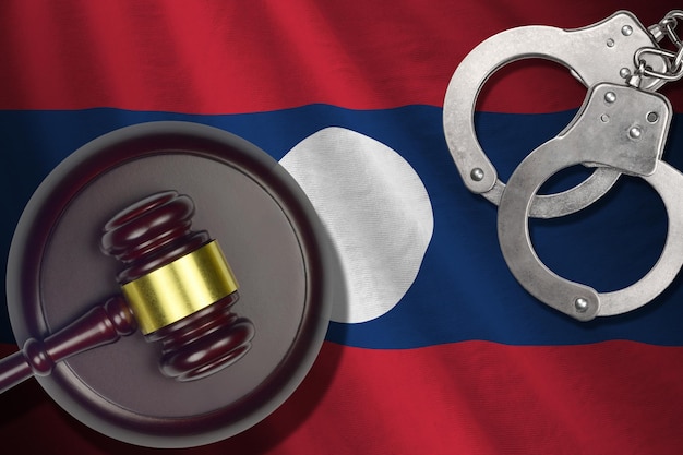 Laos flag with judge mallet and handcuffs in dark room Concept of criminal and punishment background for judgement topics