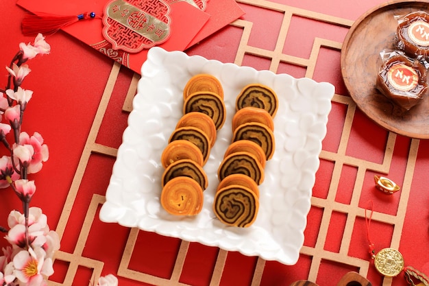 Photo lapis legit roll cake or indonesian thousand layer roll cake in a white plate on red background. this cake served on chinese new year (imlek) celebration concept