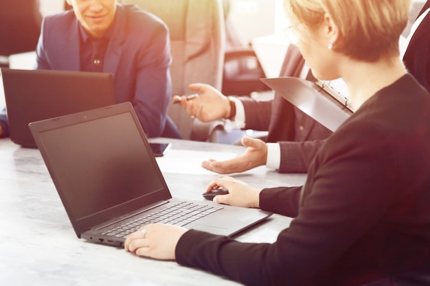 Foto computer portatile contro un gruppo di giovani uomini d'affari in ufficio che discutono insieme di un'idea di lavoro