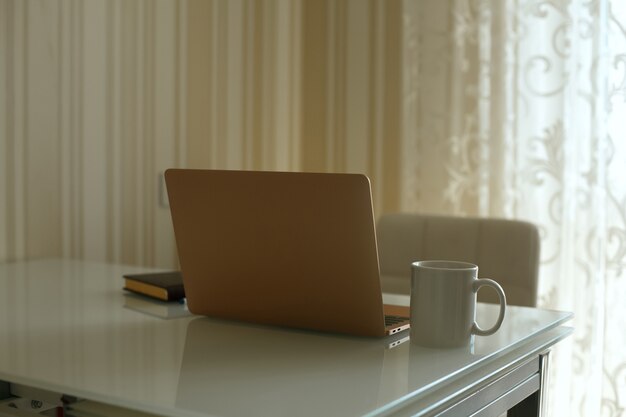 Laptop, agenda en een kopje thee op de keukentafel. Thuiswerken tijdens quarantaine