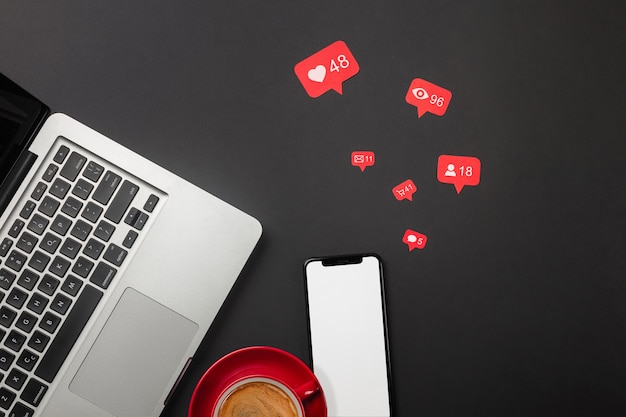 Laptop on a black desktop with a cup of coffee, a phone and a wi-fi sign, work in social networks. Top view. High quality photo