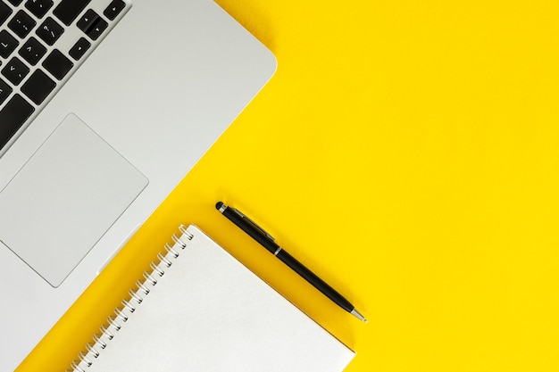 Photo laptop and blank notepad on yellow background flat lay