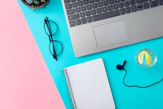 Laptop, bril, notebook, microfoon en een glas water