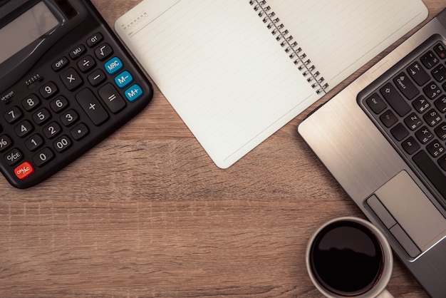 Laptop calculator and cup of coffee on table top view.