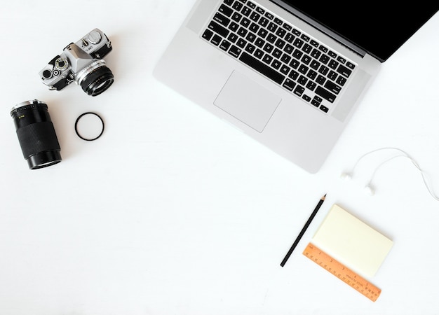 laptop and camera with sticky note pad and pencil top view mockup