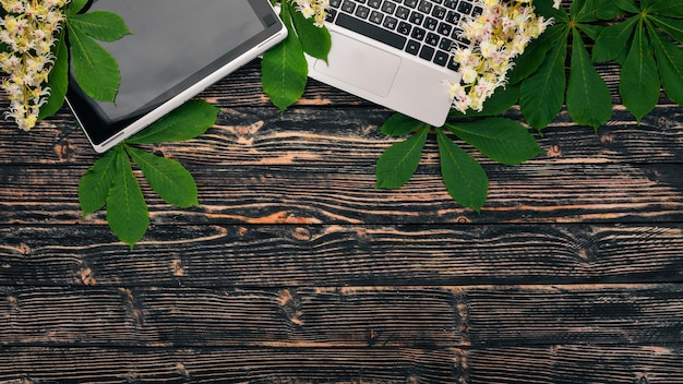 Laptop e fiori di castagno su uno sfondo di legno vista dall'alto copia spazio