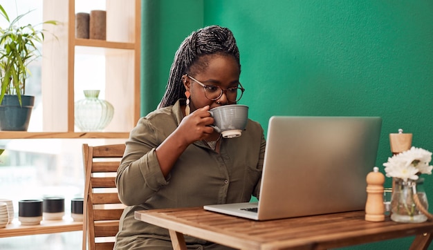 カフェでラップトップコーヒーと黒人女性とフリーランスの仕事メールを読みウェブ記事の計画コンピュータ飲みレストランの女の子オンラインコンサルティングネットワーキングリモートワーク