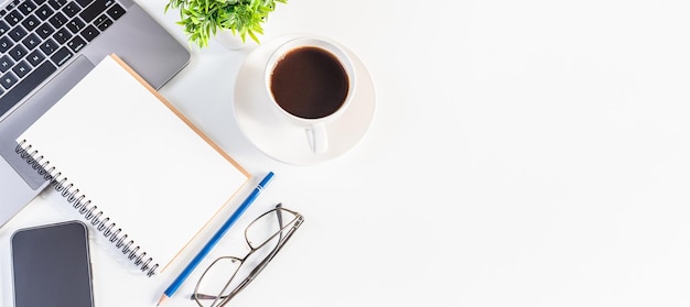 Laptop and coffee cup on a white table in the office Working concept using technology smartphones