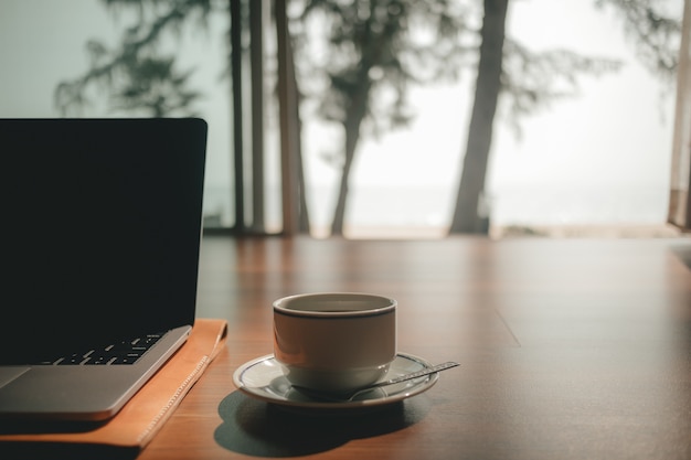 Computer portatile e tazza di caffè sul pavimento di legno