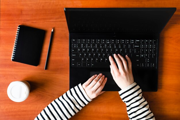 Laptop, coffee, notepad and female hands