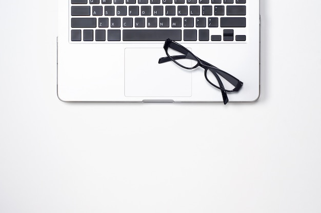 laptop computer and black glasses on white 