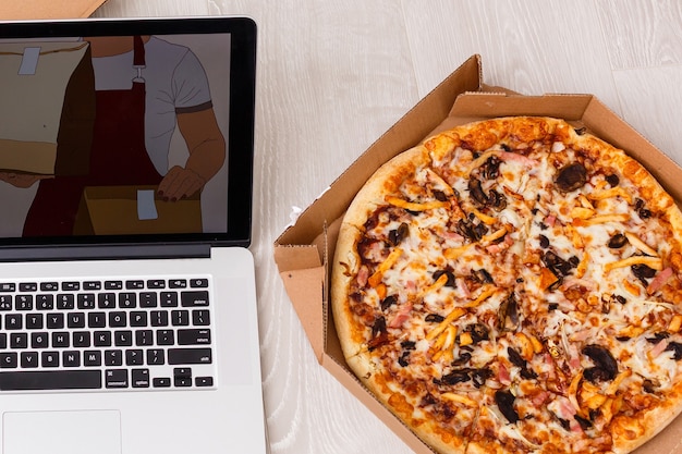 Foto primo piano del computer portatile con una pizza appetitosa su fondo bianco