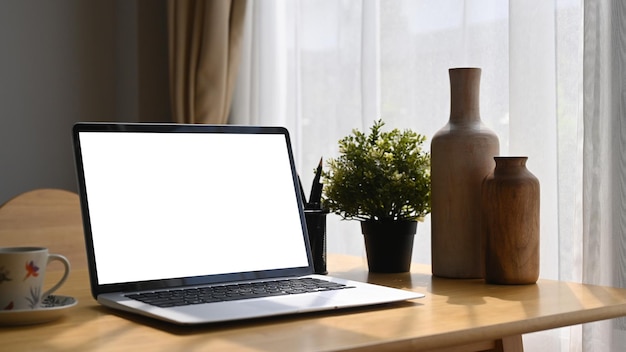 편안한 직장에서 나무 책상에 노트북 컴퓨터 커피 컵과 화초