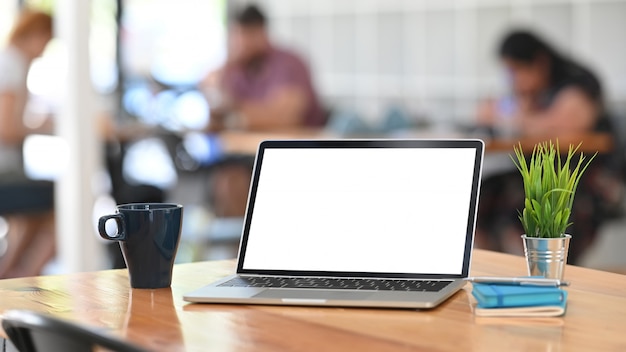 Портативный компьютер, кофе, тетрадь и ручка на деревянном столе на предпосылке деятельности co.