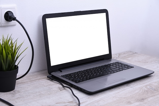 Фото Ноутбук, компьютер заряжается от 220-вольтовой розетки на столе возле стены. энергия, накопление.
