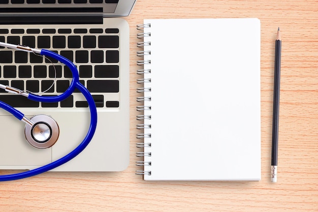 Laptop computer stethoscope and notebook on office desk