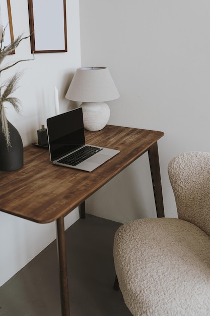 Laptop computer on table with lamp and comfortable chair Aesthetic home office workspace interior design Online shopping online store social media blog branding