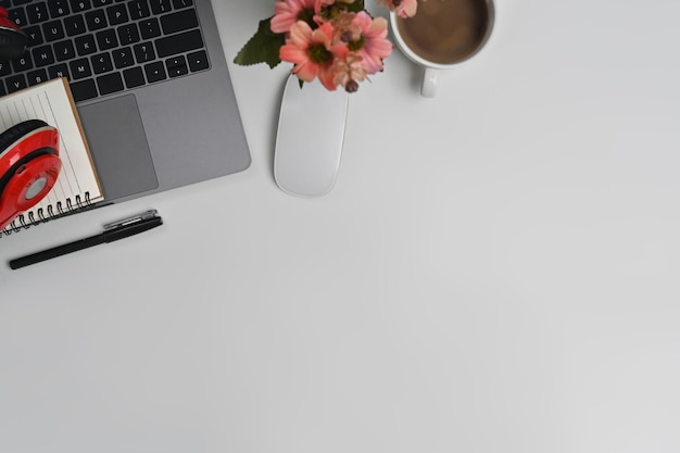 Laptop computer wireless headphone notepad and coffee cup on white office desk Top view with copy space