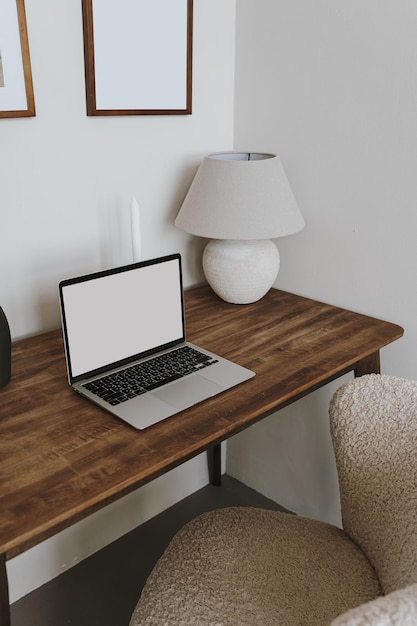 Laptop computer with blank copy space screen on table with lamp and comfortable chair Aesthetic home office workspace Online shopping online store social media blog branding mockup template