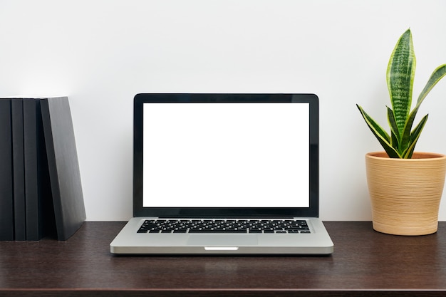 現代の職場の机の上に空白の空の白い画面ディスプレイを備えたラップトップコンピュータ。