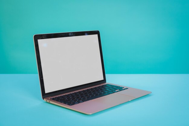Laptop computer with blank screen on aztec green paper background