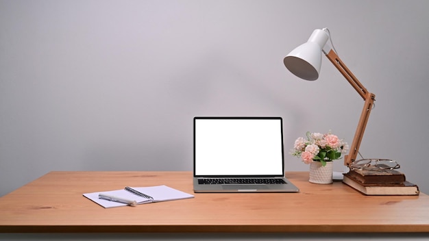 Laptop computer with blank screen notebook and lamp on wooden table