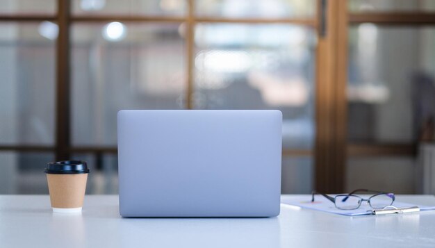 Laptop computer with paperwork eye glasses and coffee cup on the table in office