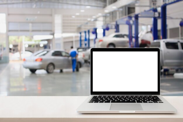 Photo laptop computer on wooden table with blurred car service centre background