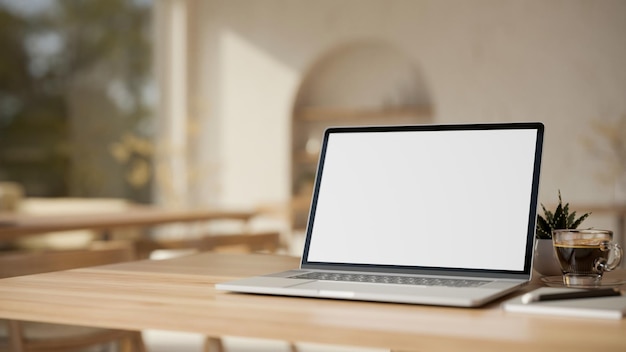 Laptop computer on wooden tabletop over blurred modern minimal cafe in background