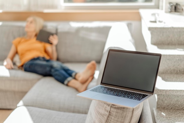 Photo laptop on couch with woman in background