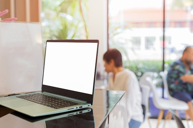 Photo laptop on counter bar with blurred customer in coffee shop.