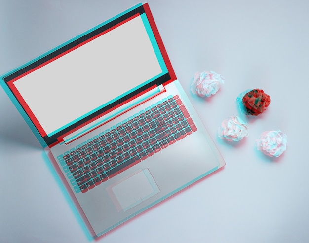 Laptop and crumpled paper balls on gray background. Minimalistic business concept. Glitch effect. Top view