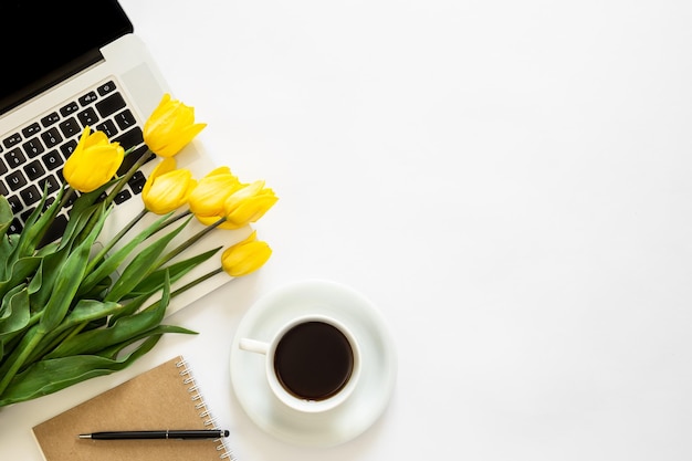 Ноутбук чашка кофе и букет тюльпанов на белом фоне вид сверху