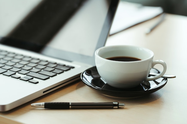 Laptop and cup of coffee on old wooden table