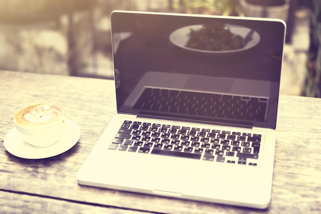 Laptop and cup of coffee on a wooden table